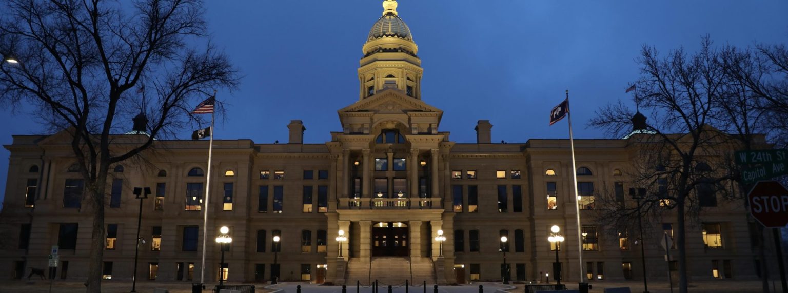 The front facade of the Wyoming State Capitol in cool blue evening light.