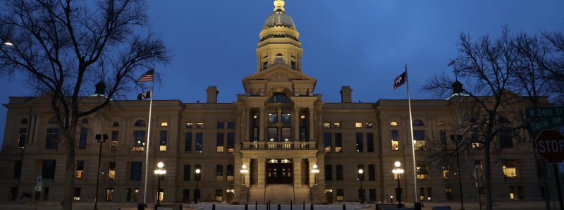 The front facade of the Wyoming State Capitol in cool blue evening light.